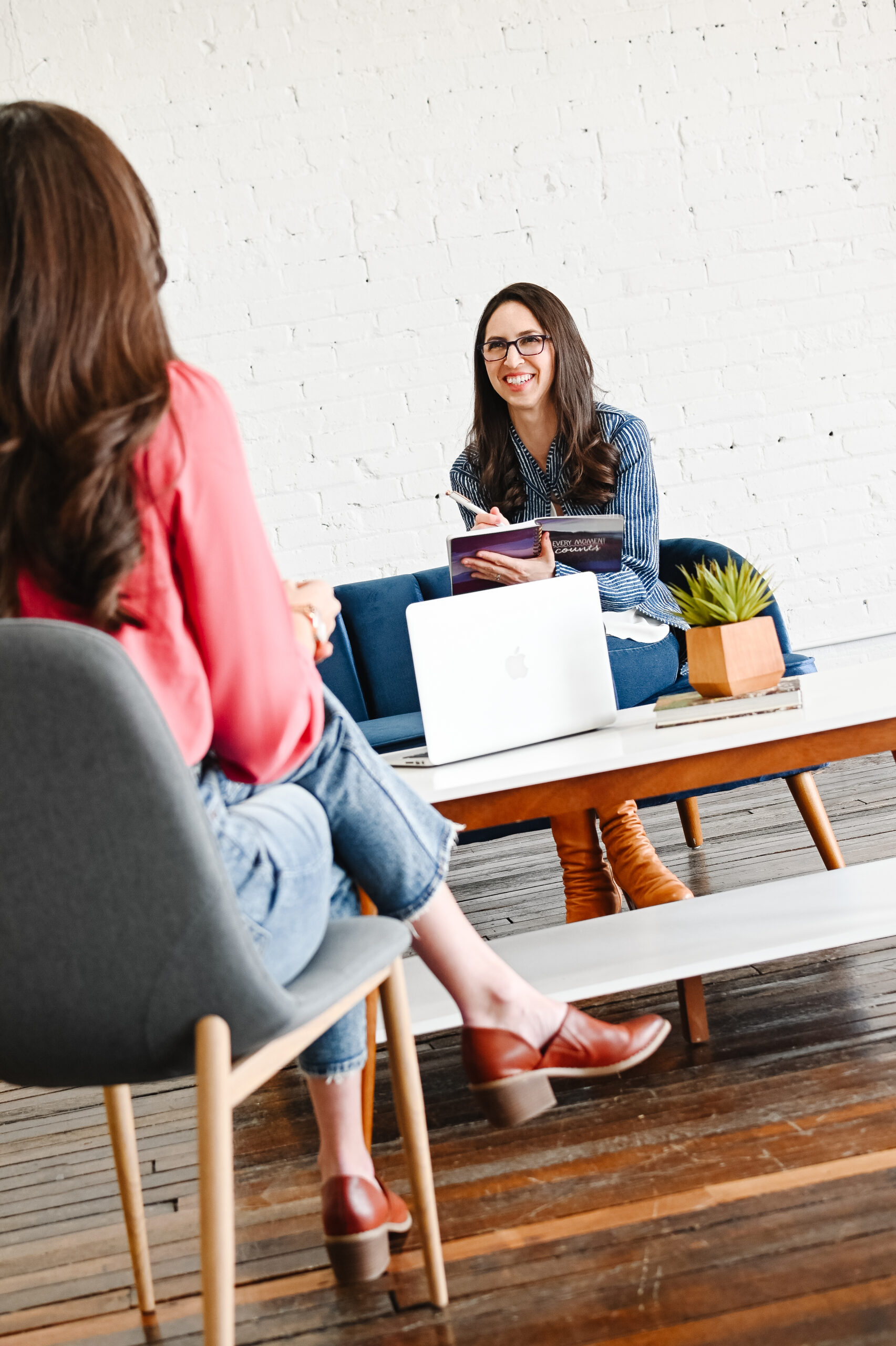 Jennifer Dawson, Web Designer, in a meeting with a client at a coffee table with a laptop